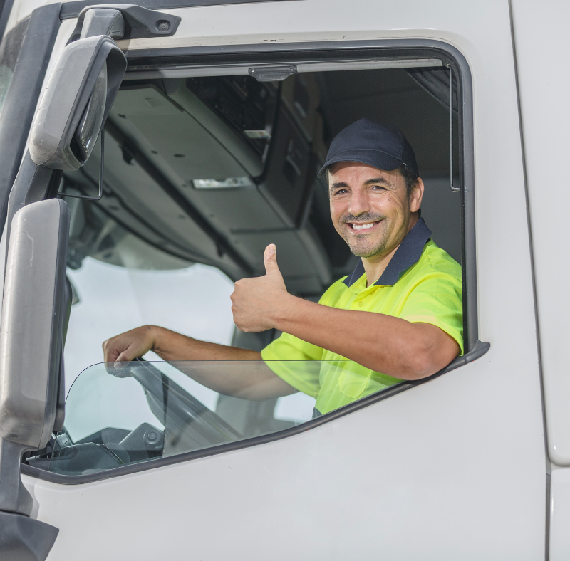 Smiling man giving thumbs up while driving his 18 wheeler truck